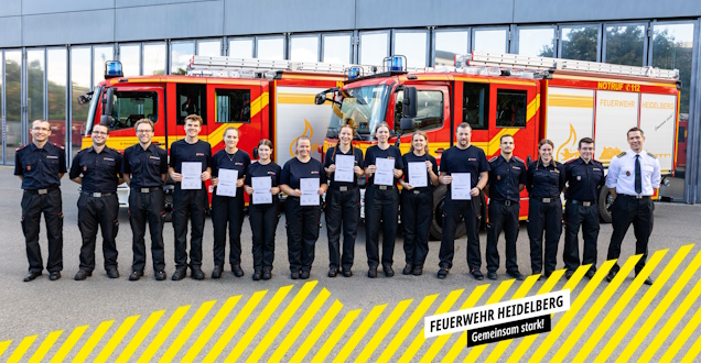Die Lehrgangsteilnehmer zeigen ihre Urkunde bei einer Gruppenaufnahme vor einem Löschfahrzeug